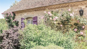 Un bâtiment traditionnel en pierre, avec un toit en tuiles, une porte en bois et une fenêtre avec des volets.