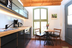 Et moderne køkken med træbordplade, sorte skabe og et vindue med grøn ramme.