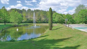 Un parque con un estanque, una fuente y una cancha de baloncesto.