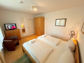 A hotel room with a bed, a TV, a wardrobe, and a mirror.