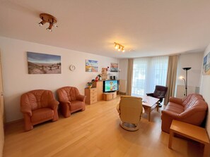 A spacious living room with leather sofas, a wooden coffee table, and a television.