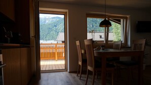 Un comedor con mobiliario de madera, una mesa, sillas y vistas a montañas a través de una ventana.