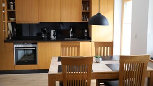 Una cocina moderna con armarios de madera, horno empotrado y comedor con sillas y mesa de madera.