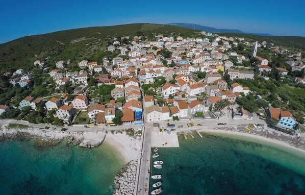 Situated on a hillside, this coastal town offers a compact, community-oriented design with a waterfront featuring a pier and boats.