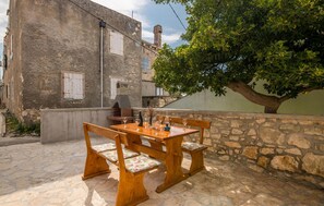 Enjoy al fresco dining under the shade of a large tree, with a stone oven nearby.
