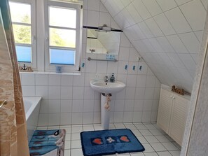 Un baño con ventana, lavamanos y perchero.