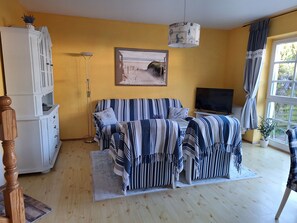 Una sala de estar con un sofá, televisor y un cuadro en la pared.