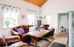 A spacious living room with a brown leather sofa set, a wooden coffee table, and a chandelier. - 2 bedroom cozy home in Lyrestad (Lyrestad)