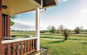 A covered porch with a view of a grassy field and distant buildings. - 2 bedroom cozy home in Lyrestad (Lyrestad)