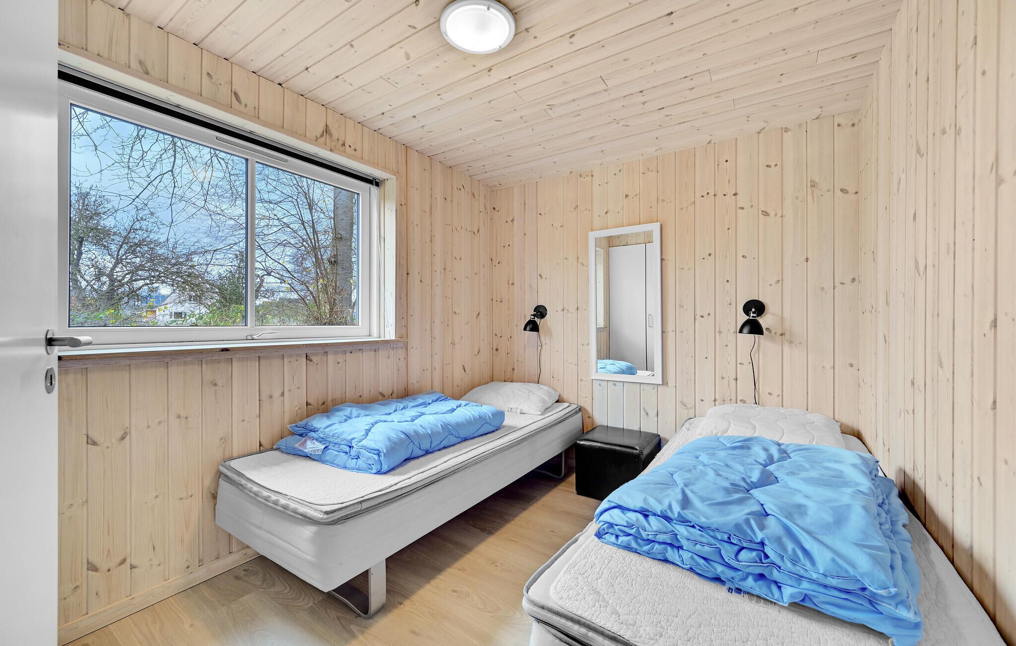 Una habitación con dos camas, una ventana y un espejo.