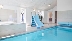 An indoor swimming pool with a blue slide, a hot tub, and a view of the outside through a door. - Stunning home in Tranekær with sauna (Tranekær)