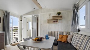 A modern living room with a dining table, sofa, and a small kitchen area.