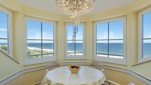 A corner room with a round table, four chairs, a chandelier, and large windows overlooking the sea. - Dune Residence A 20 - DR A 20 (Heringsdorf)
