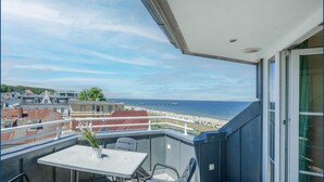 A balcony with a table and chairs overlooking a beach and cityscape. - Dune Residence A 20 - DR A 20 (Heringsdorf)