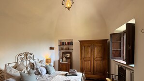 Un dormitorio con cama, lámparas de noche, un armario de madera, una estantería y una ventana con vistas.