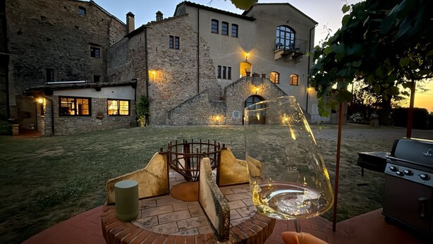 Un patio con una mesa de piedra, una copa de vino y una parrilla.