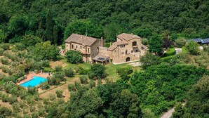 Una villa grande y rústica con piscina, rodeada de un bosque denso.
