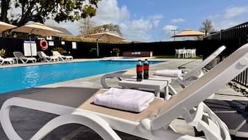 Una piscina al aire libre, sombrillas, sillones reclinables de piscina