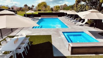 Alberca al aire libre, sombrillas en la alberca y camastros