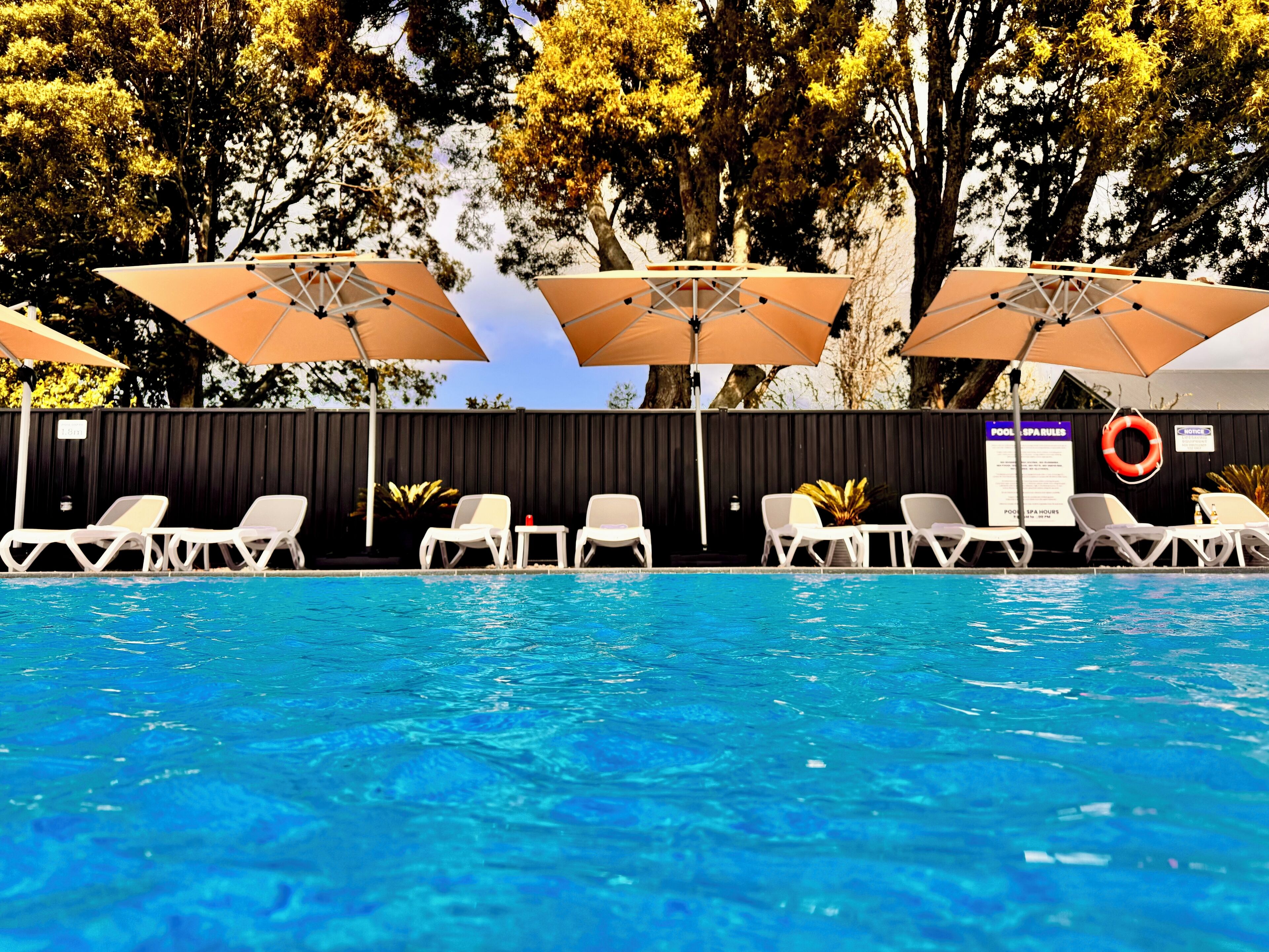 A swimming pool with lounge chairs and umbrellas.