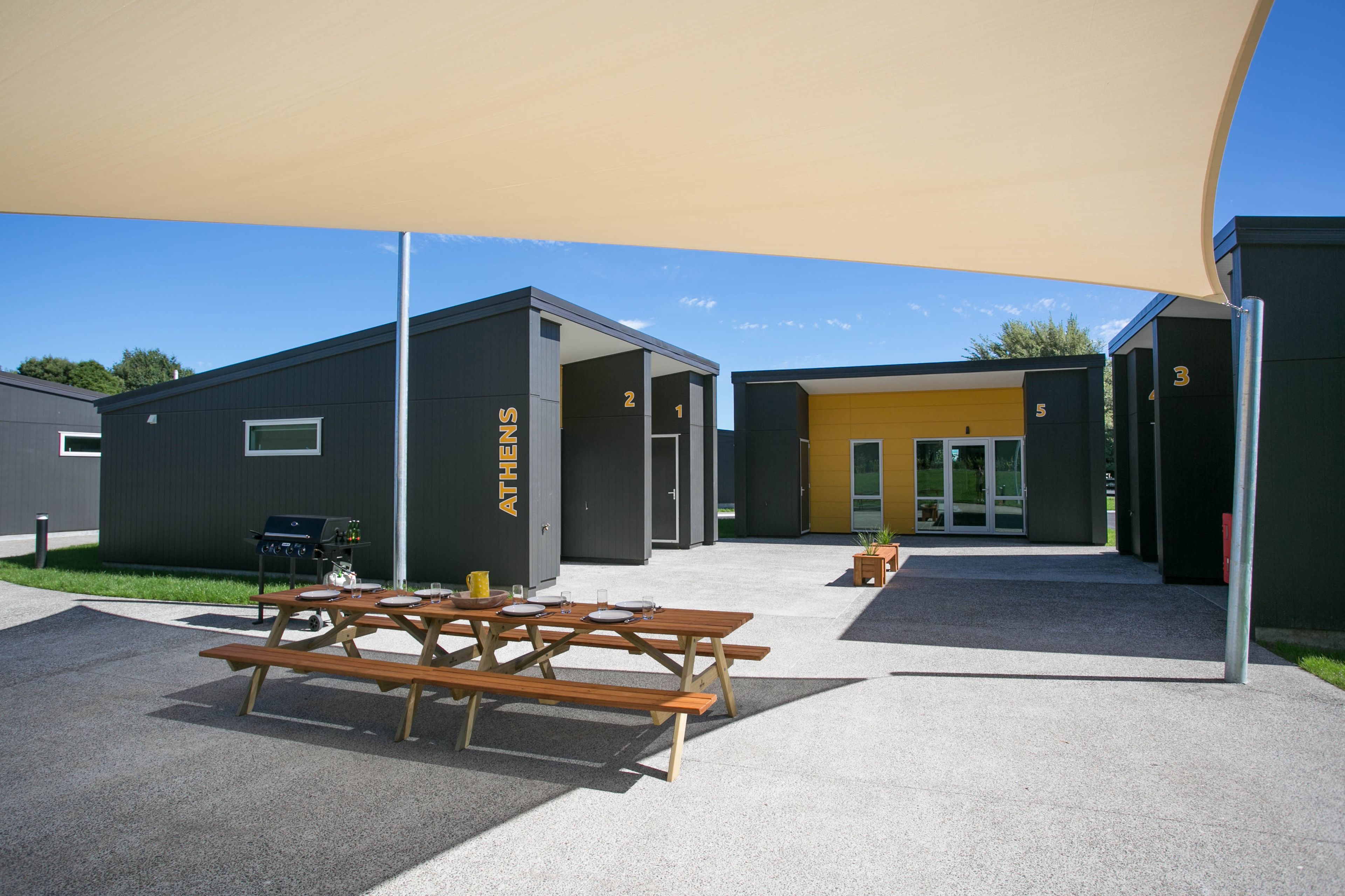 Un bâtiment moderne doté d’unités numérotées, d’un espace extérieur aménagé pour s’asseoir et d’un patio couvert.