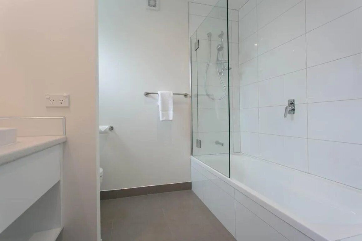 Un bagno moderno con cabina doccia in vetro, lavandino bianco e porta asciugamani.