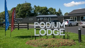 A sign for Podium Lodge with a clear view of the building and parking area. - Podium Lodge (Cambridge)