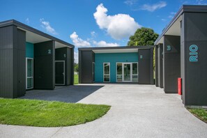 A modern building with numbered units, a central entrance, and a clear sky.