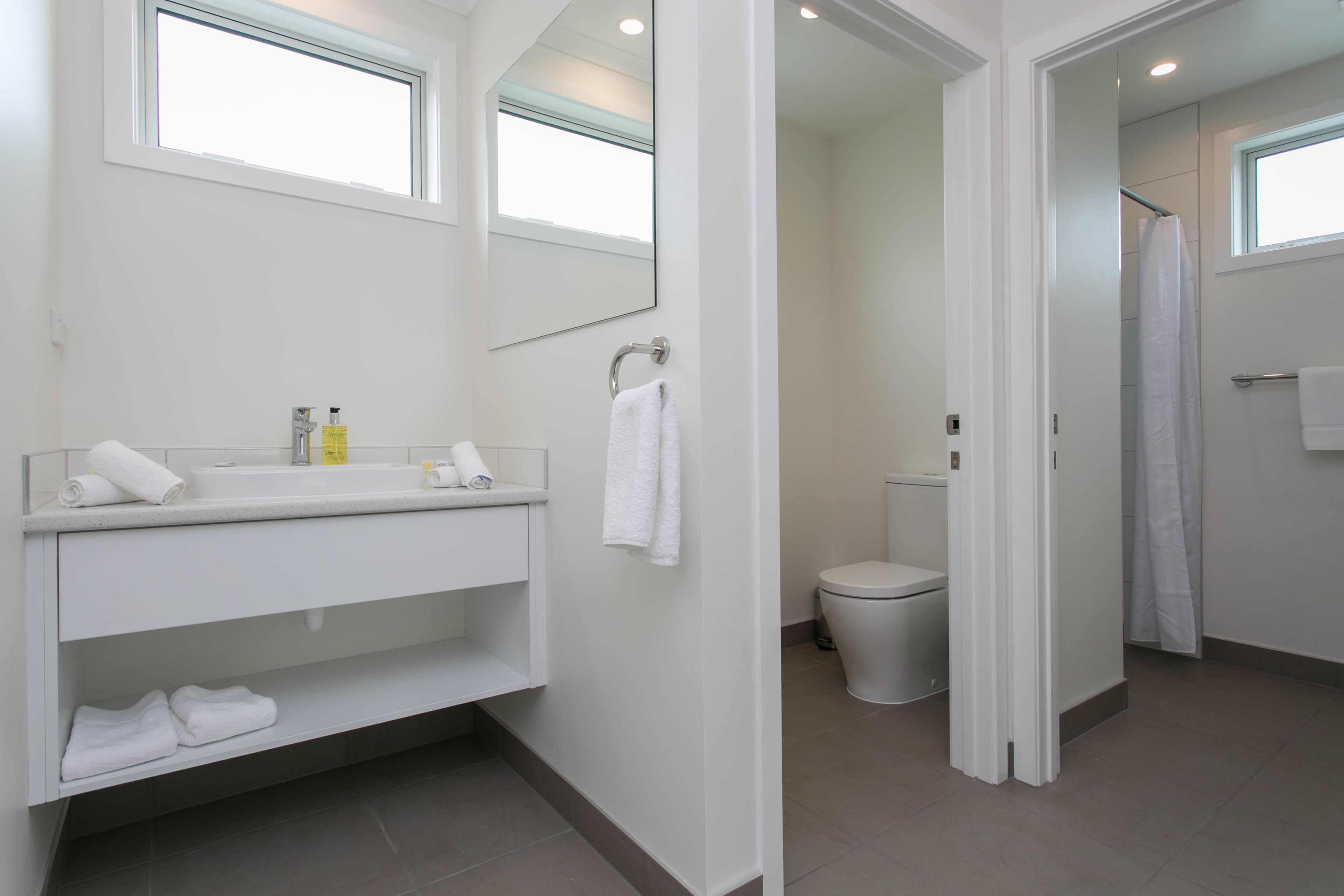 A modern bathroom with a white vanity, a toilet, and a shower area.