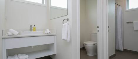 A modern bathroom with a white vanity, a toilet, and a shower area.