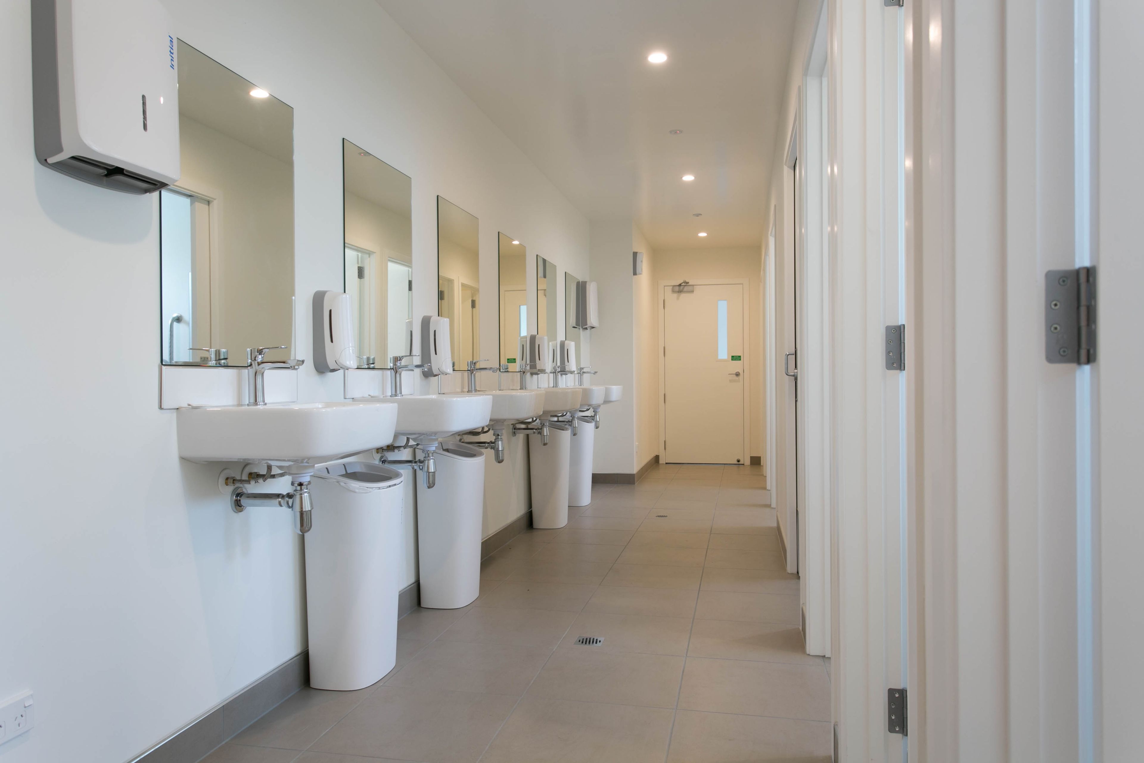 Een schone, moderne badkamer met meerdere wasbakken, spiegels en vuilnisbakken.