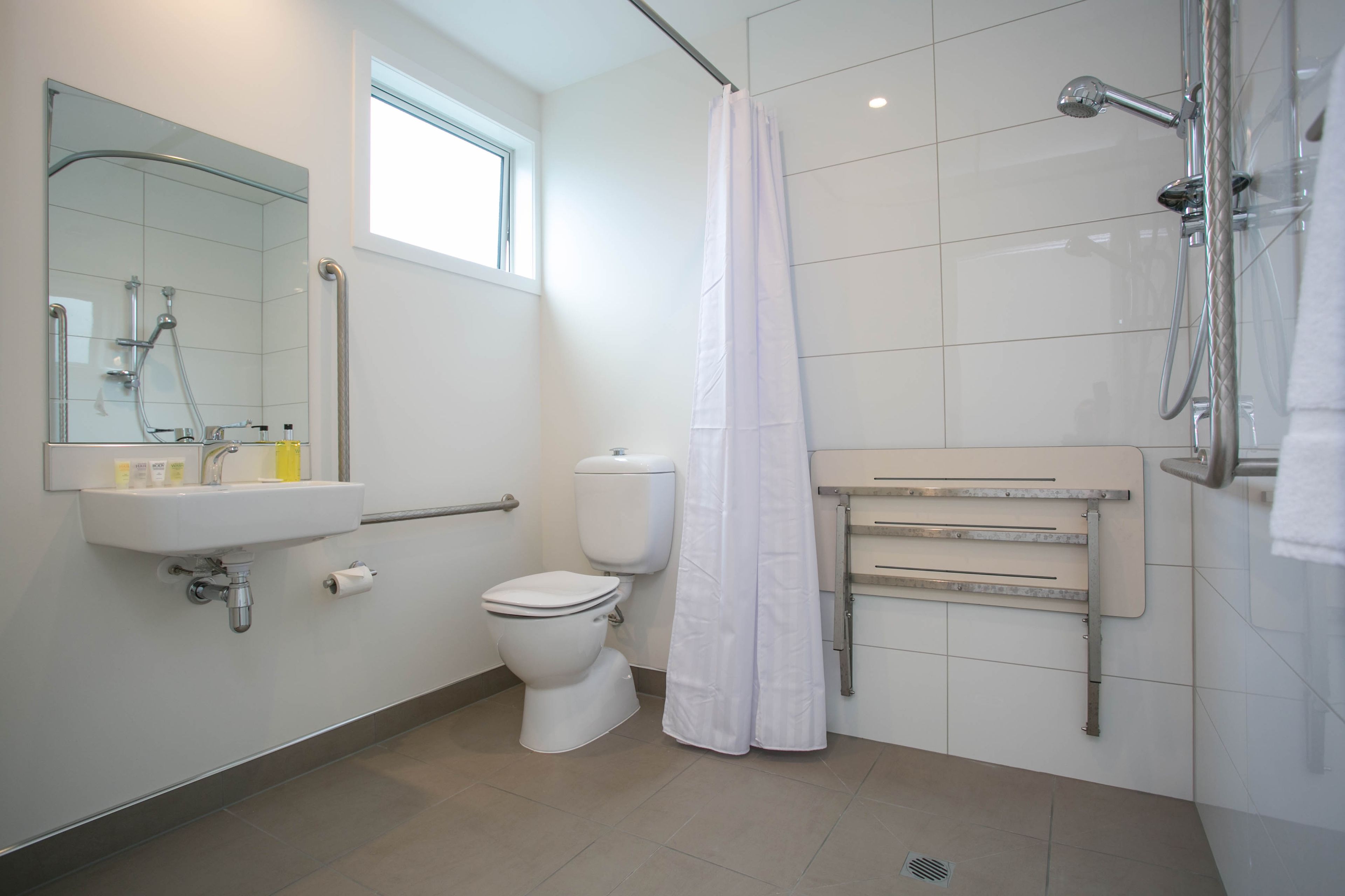 A modern bathroom with a white sink, toilet, and shower area.