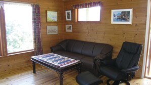 A cozy room with a wooden floor, a sofa, a chair, and a table with a blanket. - 2 bedroom beautiful home in Balestrand (Balestrand)