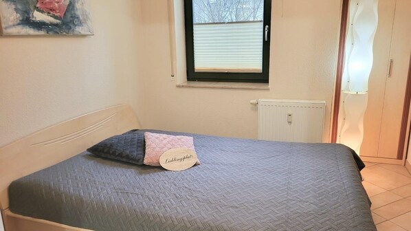 A bedroom with a bed, a window, a radiator, and a door. - (212) 3- Room Apartment - Apartment Villa Laura (Kühlungsborn)