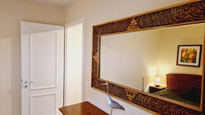 A room with a large mirror, a wooden side table, a door, and a small lamp. - (212) 3- Room Apartment - Apartment Villa Laura (Kühlungsborn)
