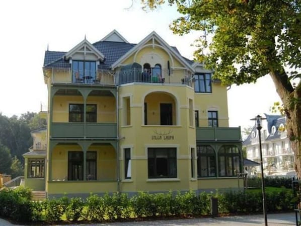 A multi-story building with a yellow facade, balconies, and arched windows.