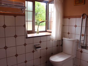 Une petite salle de bain avec des toilettes, une fenêtre avec un rideau et un porte-serviettes.