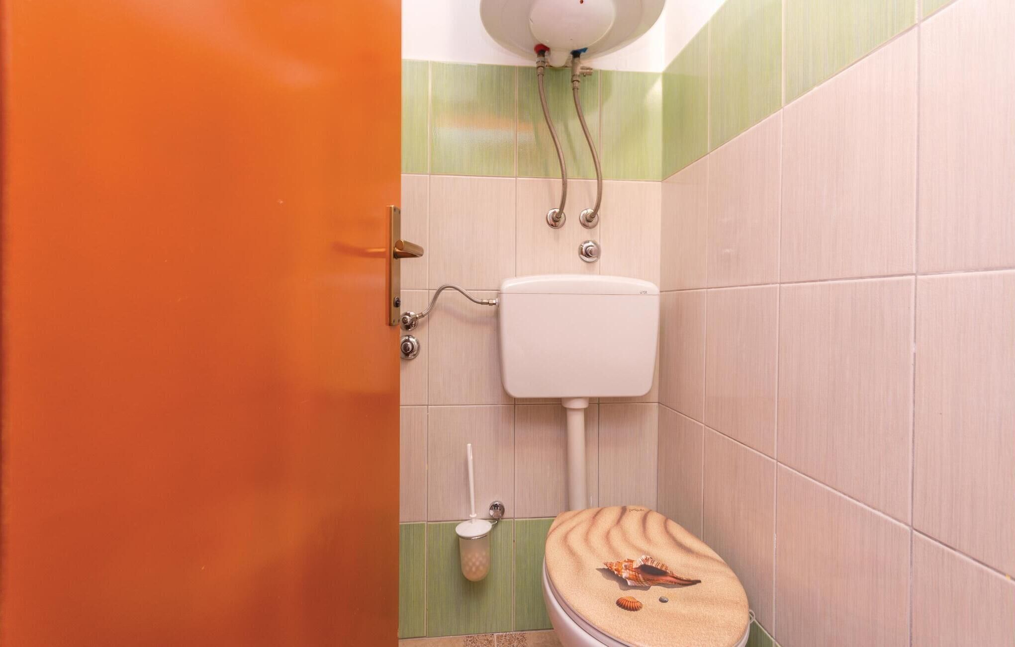 A bathroom with a toilet, a hand dryer, and a paper towel dispenser.