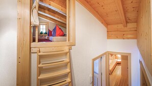A wooden interior with a loft bedroom, a wooden ladder, and a small window. - Ferienwohnung - Hoch Pustertal (Kartitsch)
