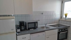 A compact kitchen with a refrigerator, microwave, coffee maker, dishwasher, and oven. - Holiday apartment for 4 people directly by the sea (Ražanj)