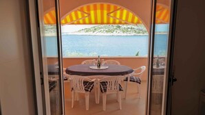 A balcony with a table and chairs, a view of the sea, and a mountainous landscape. - Holiday apartment for 4 people directly by the sea (Ražanj)
