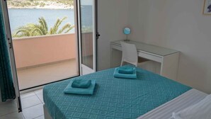 A bedroom with a bed, a desk, and a view of the sea. - Holiday apartment for 4 people directly by the sea (Ražanj)