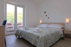 Una camera da letto con un letto, due comodini, una scrivania, due sedie e una finestra vista verde.