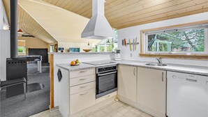 A modern kitchen with a large stove, a dishwasher, and a window overlooking greenery. - Awesome home in Væggerløse with kitchen (Væggerløse)
