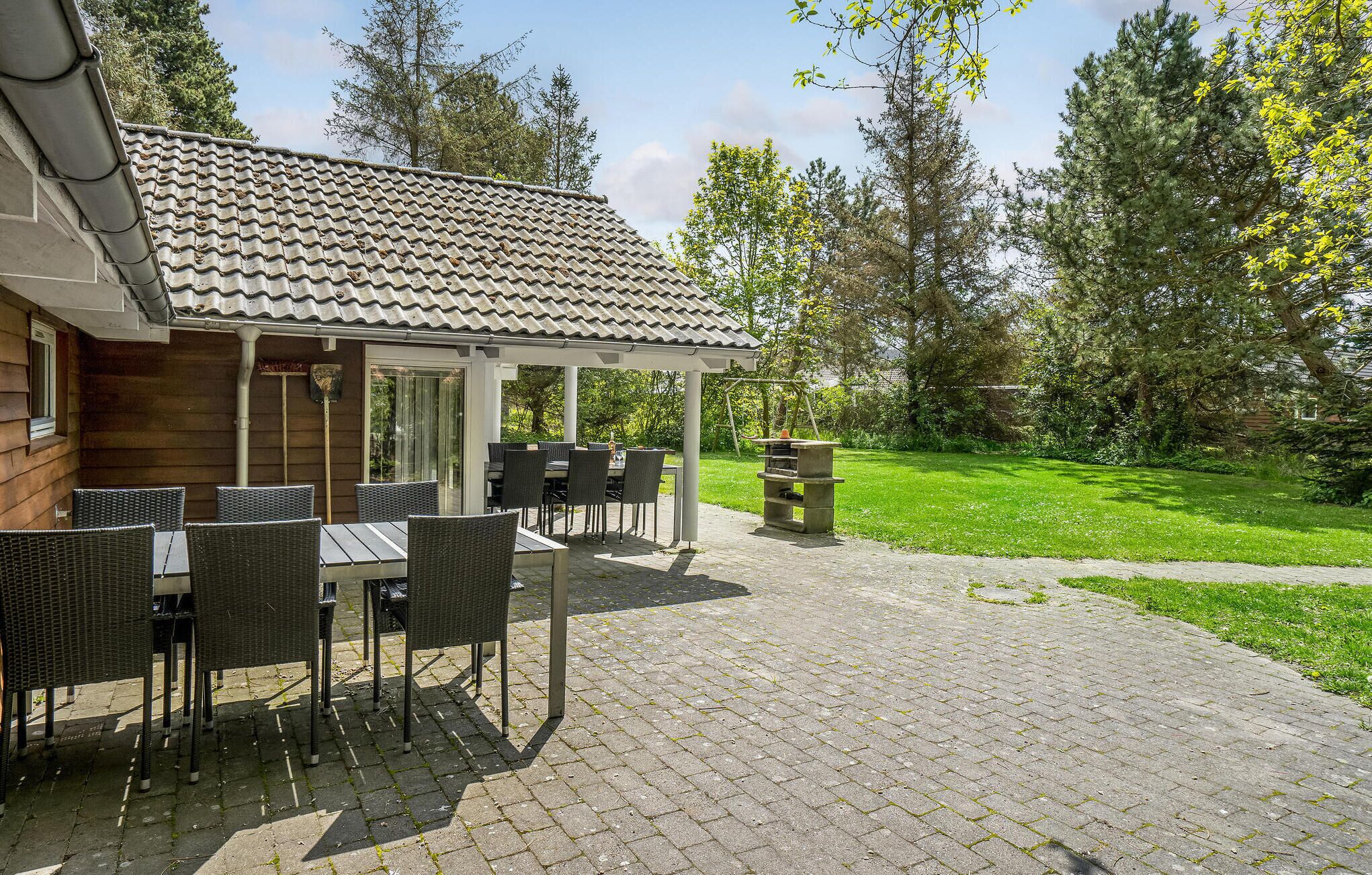 Eine Terrasse mit Gartenmöbeln, einem Grill und einem überdachten Sitzbereich.