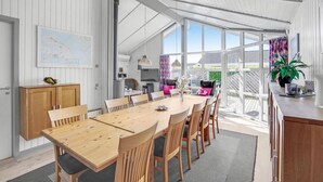 A spacious dining area with a long wooden table and chairs, large windows, and a view of the outdoors. - Beautiful home in Sydals with sauna (Sydals)