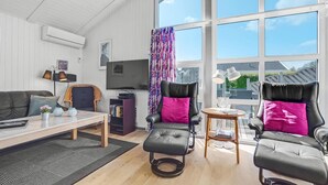 A modern living room with a sofa, two armchairs, a TV, and a large window with curtains. - Beautiful home in Sydals with sauna (Sydals)