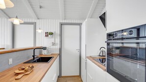 A modern kitchen with a wooden countertop, stainless steel appliances, and a white backsplash. - Beautiful home in Sydals with sauna (Sydals)