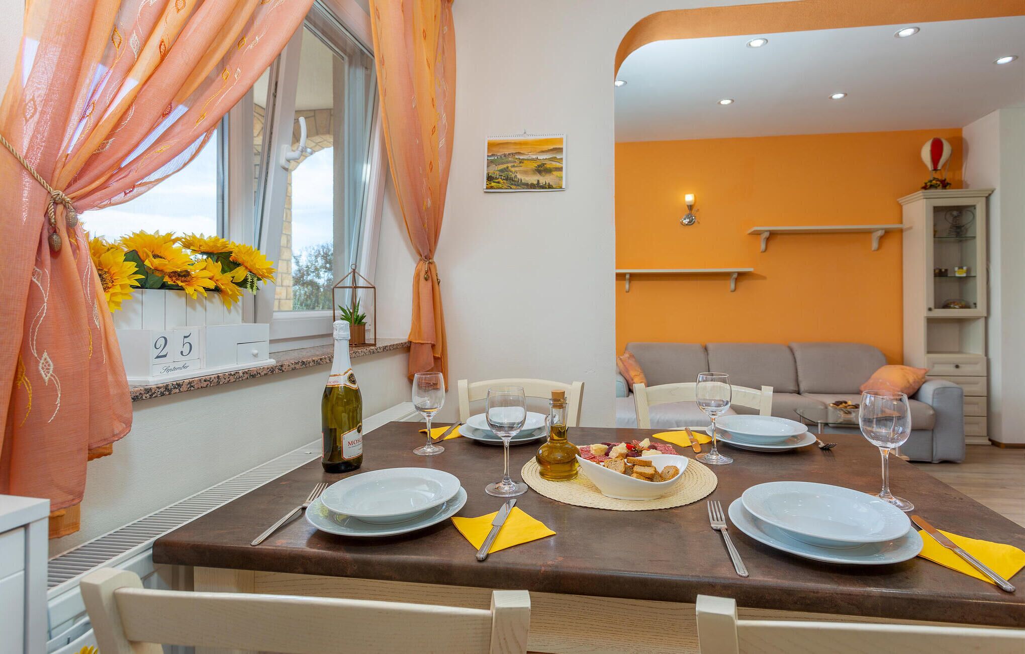 Un coin repas avec une table dressée pour quatre personnes, une bouteille de vin et un panier de pain.