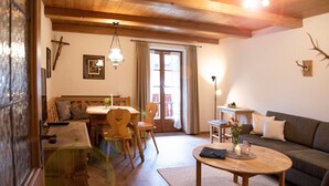 Una sala de estar acogedora con techo de madera, un comedor con mesa y sillas, y un sofá.